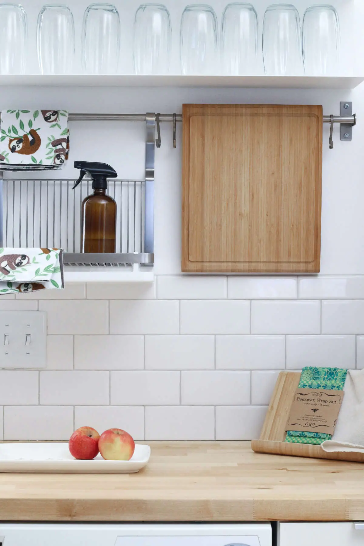 Tidy white kitchen with a spray bottle, a chopping board and apples