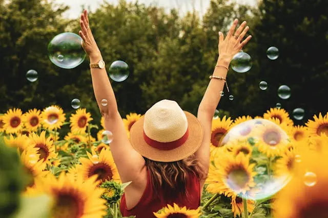 Woman in a hat with her arms raised in a field of sunflowers