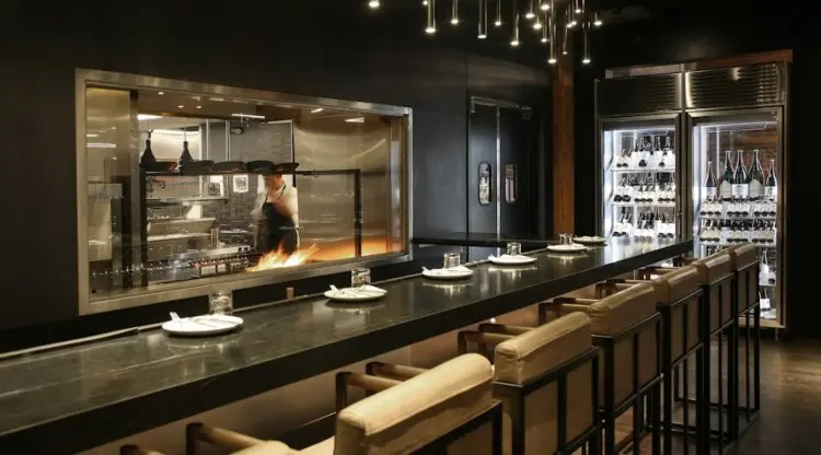 Barra de un restaurante con la cocina abierta al fondo