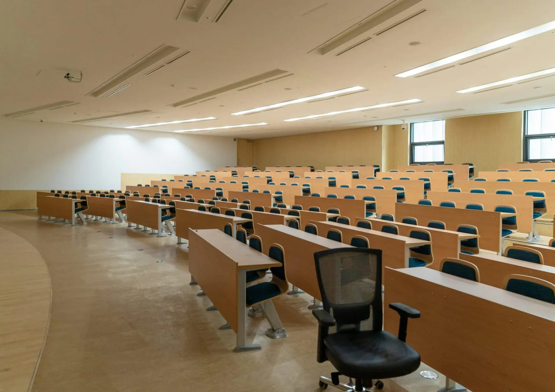 Aula universitaria vacía con filas de pupitres