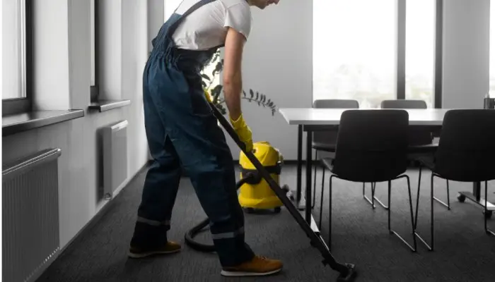 Worker vacuuming the carpet of a meeting room
