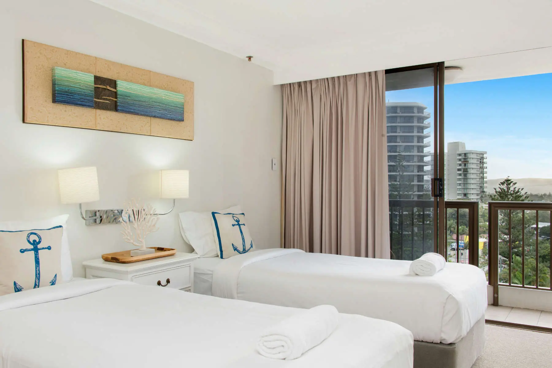 Holiday apartment bedroom with two made beds and a sea view