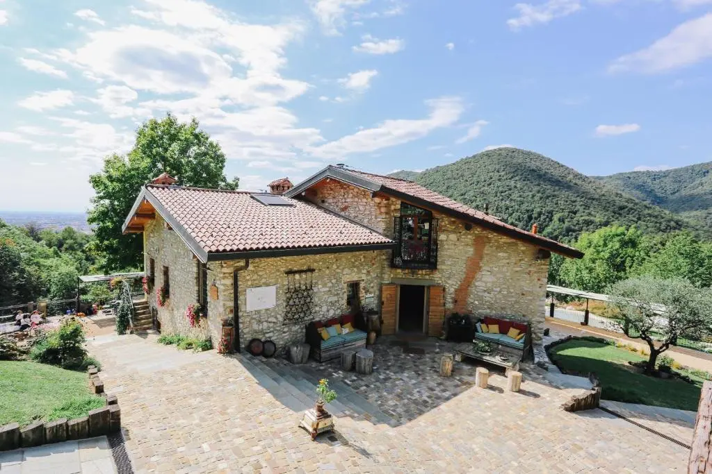 Stone house with a garden and mountains behind it