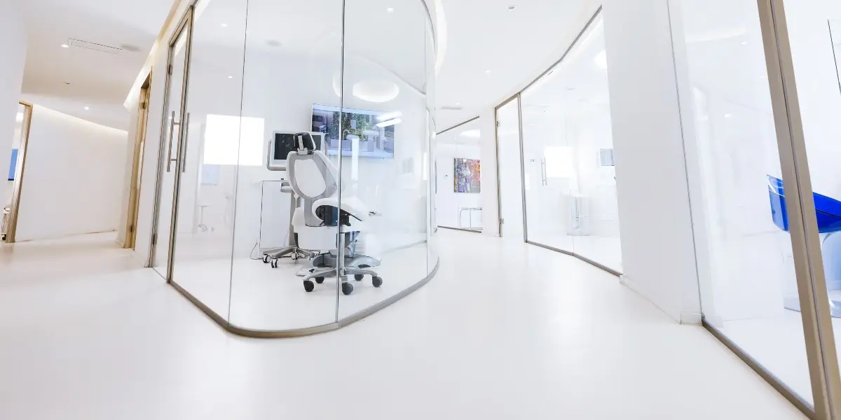 White clinic corridor with a glass-walled treatment room